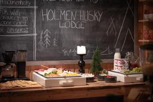 una mesa con comida en ella con una pizarra en Holmen Husky Lodge en Alta