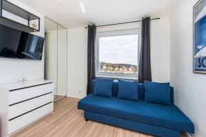 salon z niebieską kanapą i oknem w obiekcie Piękne mieszkanie z widokiem na Zatokę Gdanska-Sopot Kamienny Potok w mieście Sopot