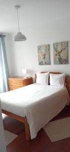 1 dormitorio con 1 cama grande con sábanas y almohadas blancas en Alojamento Pestana, en Horta