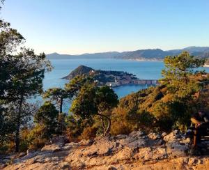 a person sitting on top of a mountain overlooking a body of water at Hotel Sereno in Sestri Levante