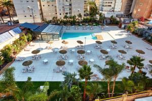 widok na basen ze stołami i krzesłami w obiekcie Les Dunes Suites w mieście Benidorm