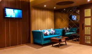 a living room with a blue couch and a tv at Rudra Shelter Business Hotel in Vasai