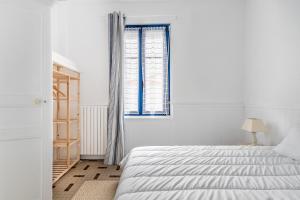 a white bedroom with a bed and a window at L'Argentine, Maison typique pour 5 a Saint Gilles-croix-de-vie in Saint-Gilles-Croix-de-Vie