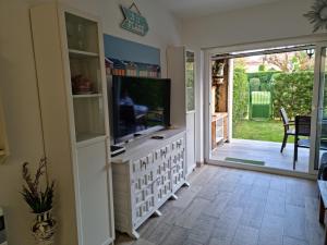 een woonkamer met een tv en een glazen schuifdeur bij Sagaro garden, Jardin privado, piscina, 150 m playa in S'Agaro