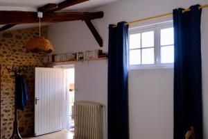 een kamer met een deur en een raam met blauwe gordijnen bij Le Clou in Chauvigny