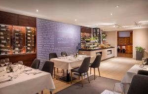 a restaurant with white tables and chairs and a kitchen at VALAMAR Obertauern in Obertauern