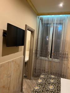 Una habitación con un televisor de pantalla plana en una pared. en Hotel Iris, en Nápoles