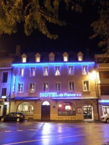 un bâtiment avec des lumières bleues à l'avant dans l'établissement Hôtel de France, à Espalion
