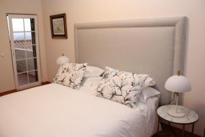um quarto com uma cama branca com almofadas e uma janela em Villa Tranberg Suites nas Ferreiras