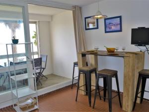 een kamer met een bar met krukken en een televisie bij Apartment Les Occitanes by Interhome in Gruissan +21 foto's