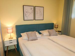 a bedroom with two beds and two lamps and two pictures on the wall at Apartment Brombeerweg by Interhome in Unterkirnach