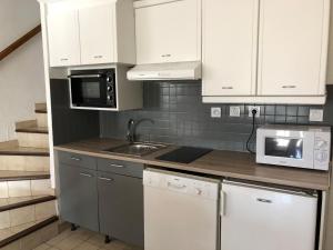 une cuisine avec des armoires blanches, un évier et un micro-ondes dans l'établissement Confort et calme à deux pas des plages de Valras, à Valras-Plage 14 autres photos