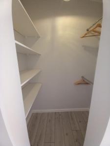 a walk in closet with white shelves and a wooden floor at Rewianka Apartamenty przy samej plaży in Rewa