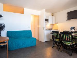 a living room with a blue couch and a kitchen at Apartment Ipanema Sud-6 by Interhome in Canet-en-Roussillon