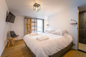 a bedroom with a large bed with white sheets at La Rigaudrye in Ellezelles