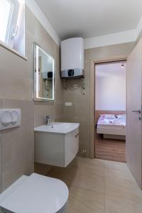 a bathroom with a sink and a toilet and a bed at Sea View Luxury Apartment in Cres