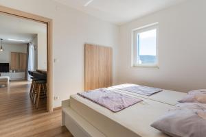 a white bedroom with a bed and a window at Sea View Luxury Apartment in Cres