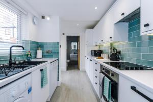 een keuken met witte werkbladen en blauwe tegels bij Phillip House in Chester