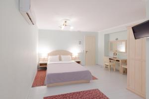 a white bedroom with a bed and a desk at 999 Luxury Hotel in Nafplio