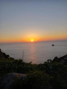 a sunset over the ocean with the sun setting at PISO FISTERRA in Fisterra