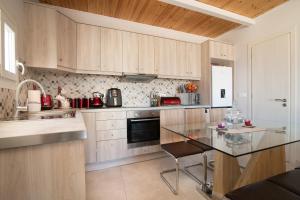 a kitchen with wooden cabinets and a glass table at Sweet Cottage Retreat in Zakynthos