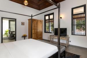 a bedroom with a bed and a tv and windows at Jetwing Mahesa Bhawan in Jaffna
