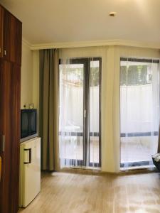a living room with a tv and a sliding glass door at Apartments Sarafovo in Burgas City