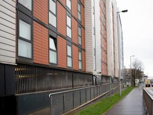 a building with a fence next to a street at Cosy 1 bed next to SEC, OVO Hydro, Finnieston - Pass the Keys in Glasgow