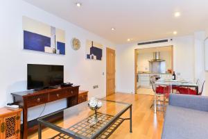 a living room with a couch and a table and a television at The Great London Apartments in London