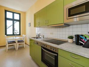 una cocina con armarios verdes y una mesa con ventana en Strandvilla Ostpreussen - Dependance Strandhus, en Ahlbeck