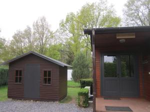 a smallshed with a door next to a building at Le Petit Chalet in Resteigne