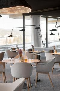 restauracja ze stołami i krzesłami oraz dużym oknem w obiekcie Hôtel des Horlogers w mieście Le Brassus
