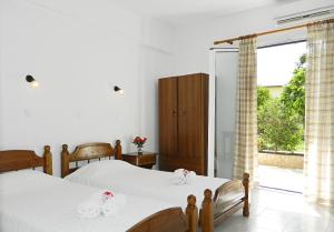 a bedroom with two beds and a large window at ARISTON APARTMENTS in Póros Kefalonias