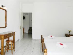 een witte slaapkamer met een bureau en een bed bij ARISTON APARTMENTS in Póros