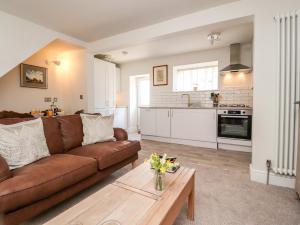 a living room with a brown couch and a table at Bay Cottage No 5 in Morecambe