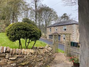 una pared de piedra junto a una casa con un árbol en The Bothy at Ivy Cottage en Haltwhistle