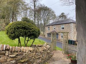 a stone wall next to a house with a tree at The Bothy at Ivy Cottage in Haltwhistle