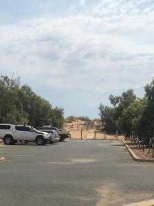 um parque de estacionamento com carros estacionados na berma da estrada em Hedland Accommodation em Port Hedland