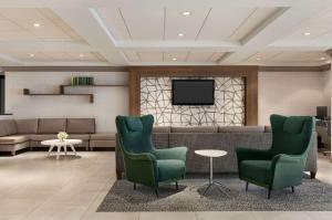 a waiting room with two green chairs and a tv at Wyndham Garden Totowa in Totowa