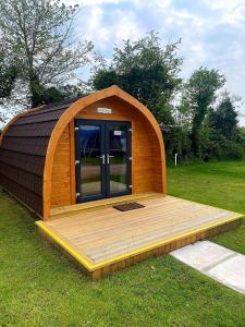 een houten hut met een houten terras in het gras bij Wall park touring Centry road camping in Brixham