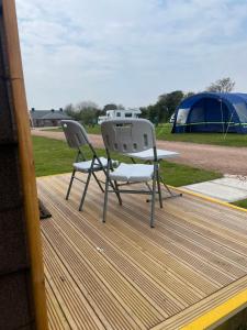 two chairs and a table on a deck with a tent at Wall park touring Centry road camping in Brixham