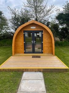 una estructura de madera con una puerta en el césped en Wall park touring Centry road camping, en Brixham