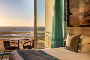een slaapkamer met een bed en uitzicht op de oceaan bij Best Western Plus Hotel Canet-Plage in Canet-en-Roussillon