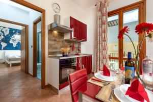una cocina con armarios rojos y una mesa con una silla roja en Residence I Tesori di San Vito, en San Vito lo Capo
