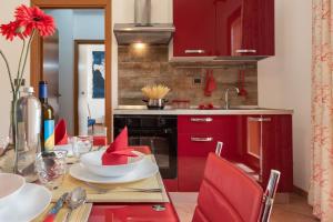 a kitchen with red cabinets and a table with red chairs at Residence I Tesori di San Vito in San Vito lo Capo