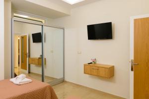 a bedroom with a bed and a television on the wall at Melia deluxe city view apartment in Agios Nikolaos