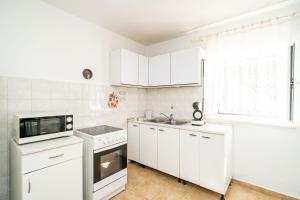 a kitchen with white cabinets and a sink and a microwave at Apartment Kos in Dubrovnik