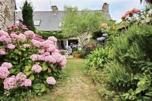 un giardino con fiori rosa di fronte a una casa di La chambre du capitaine a Plérin