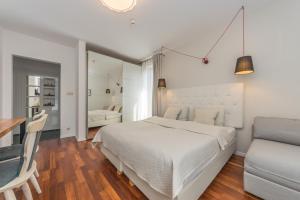 a white bedroom with a bed and a couch at Aparthotel Luna&Sol in Jastrzębia Góra