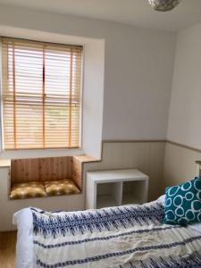 a bedroom with a bed and a window with a table at The Mexico Inn, Flat One in Ludgvan